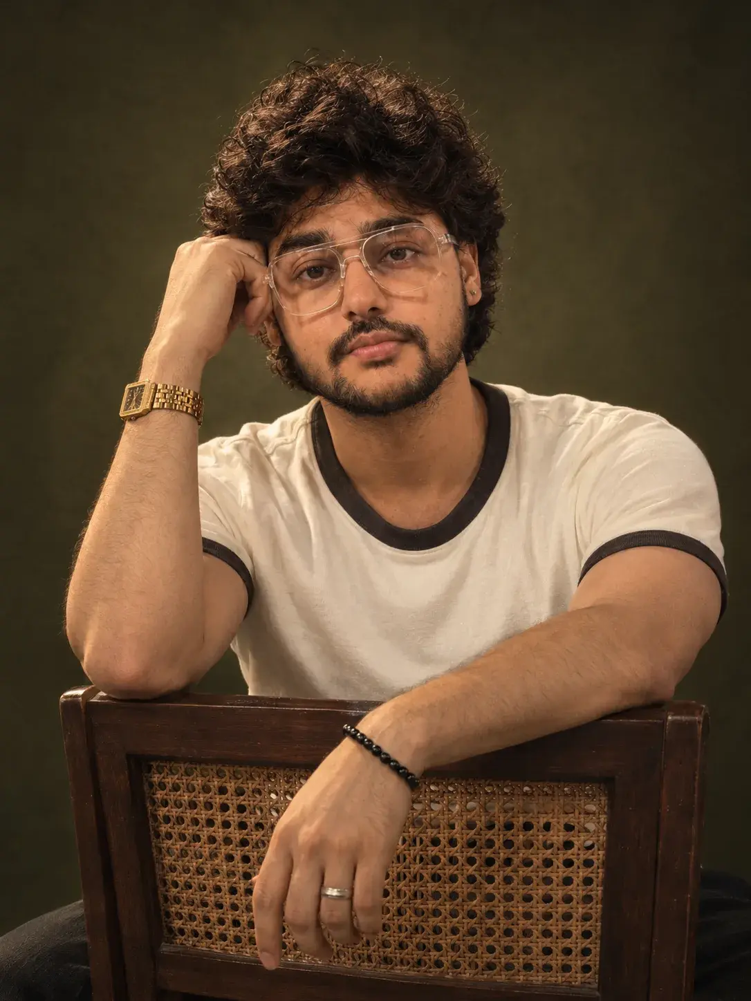 A Warm, Cinematic Studio Portrait With Editorial Pose Against The Cane-Backed Chair.