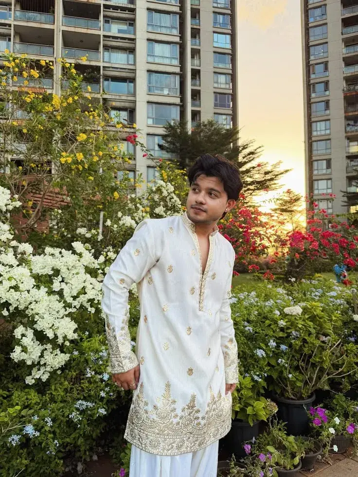 A White Kurta Stands Confidently In A Lush Garden, Surrounded By Vibrant Flowers