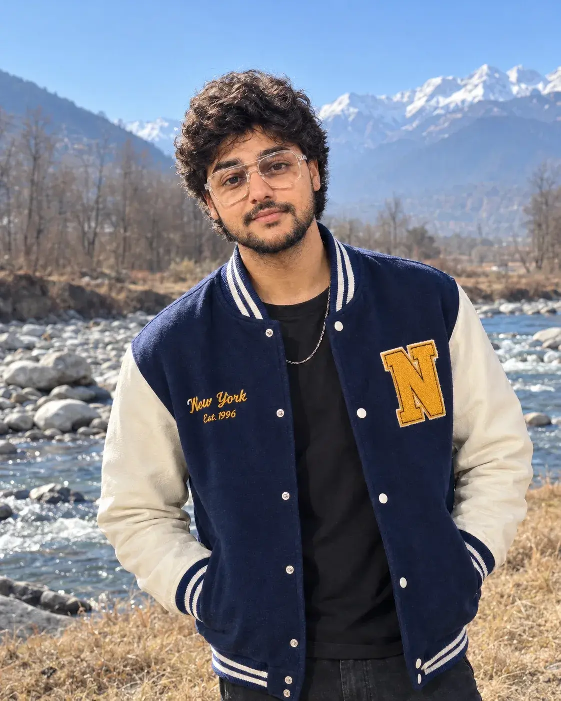 A Young Man Wears Wears A Navy Blue Varsity Jacket With Cream-White Leather Sleeves