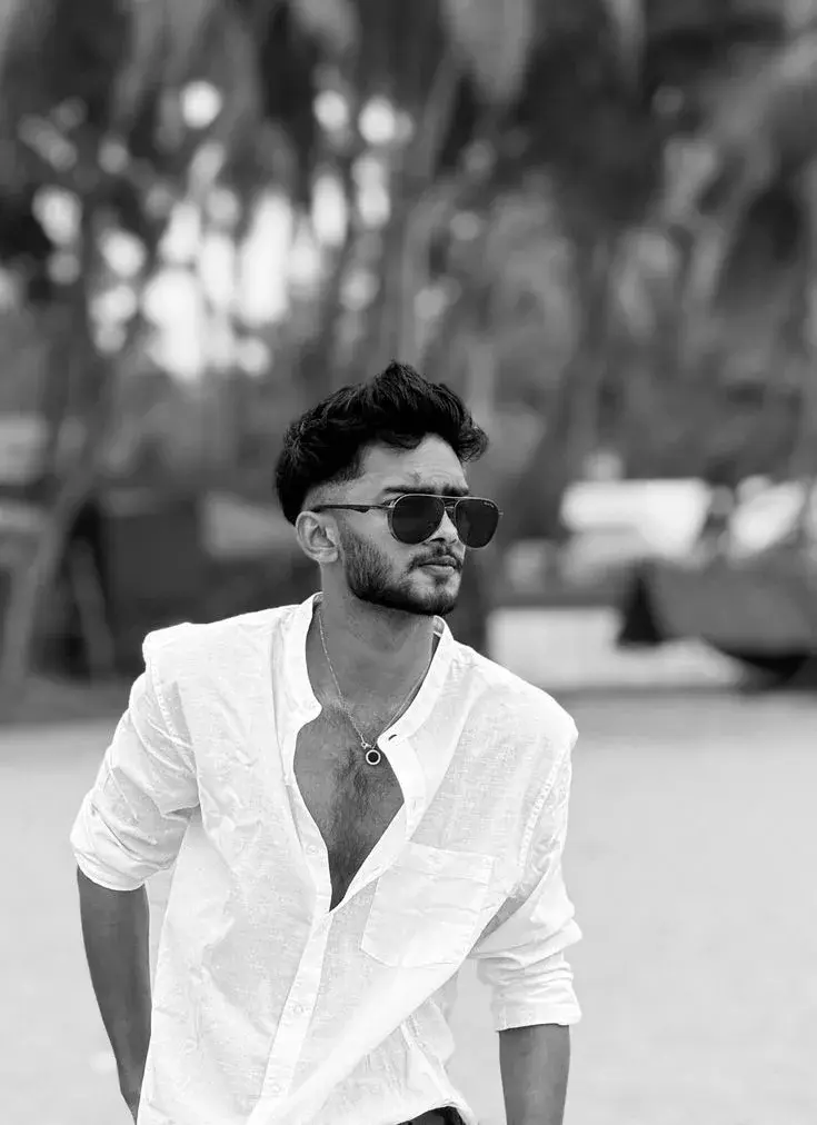 Candid Black-And-White Outdoor Beach Portrait Of Young South Asian Man In Unbuttoned Linen Shirt And Aviator Sunglasses