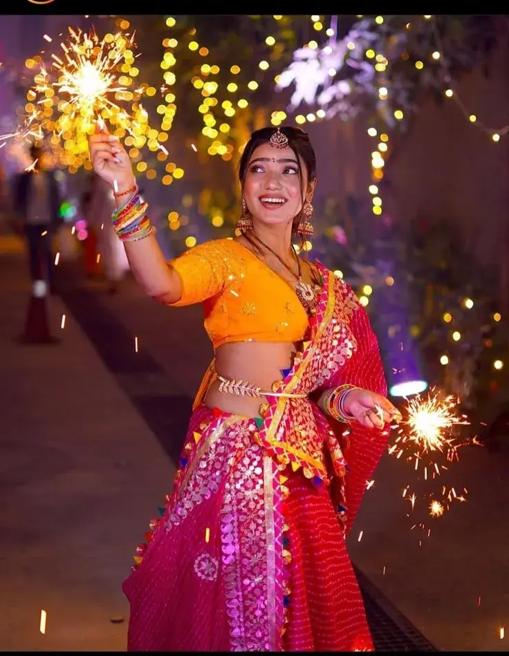 Candid Festive Diwali Portrait Of Joyful Young South Asian Woman In Pink Leheriya Lehenga Holding Burning Sparklers