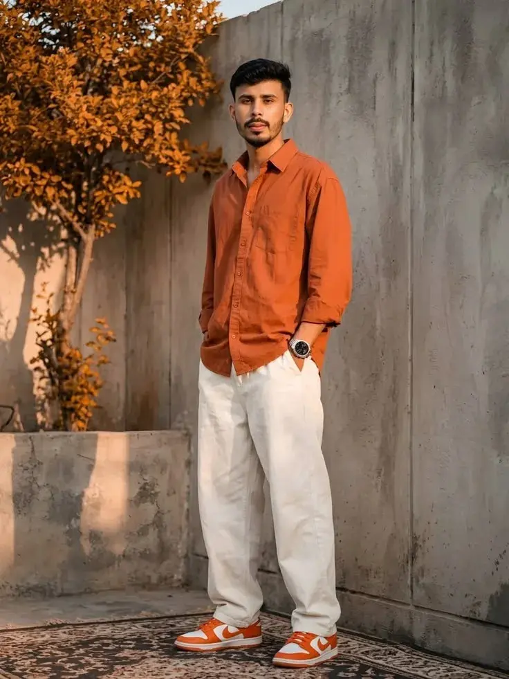 Candid Full-Length Golden Hour Streetwear Portrait Of Young South Asian Man In Rust Orange Shirt And Off-White Trousers