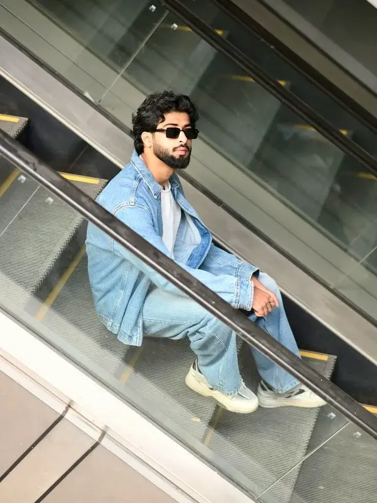 Candid Full-Length Indoor Escalator Portrait Of Young South Asian Man In Double Denim And Sunglasses