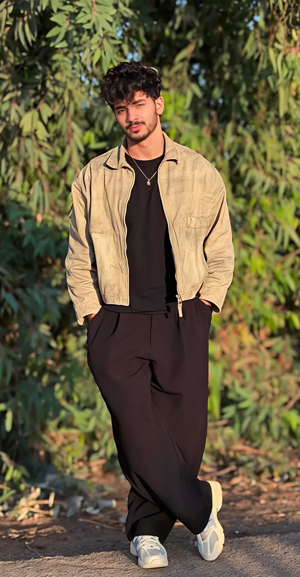 Candid Golden Hour Outdoor Portrait Of Young South Asian Man With Curly Fringe In Beige Harrington Jacket And Wide-Leg B