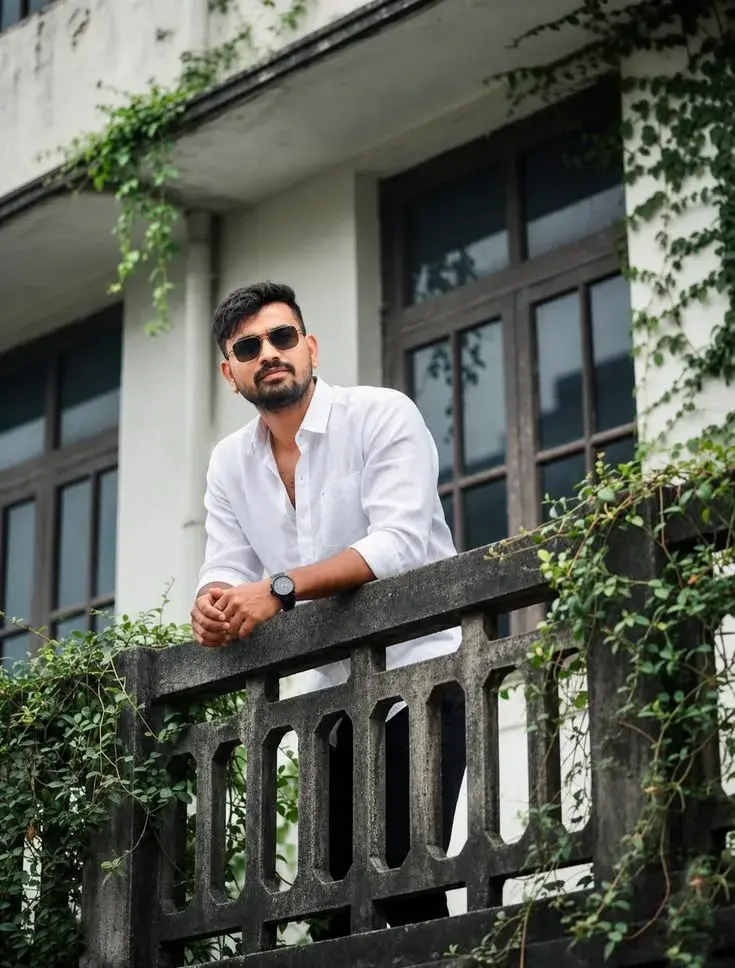 Candid Heritage Balcony Portrait Of Young South Asian Man With Sunglasses And Short Boxed Beard Leaning On Concrete Balu