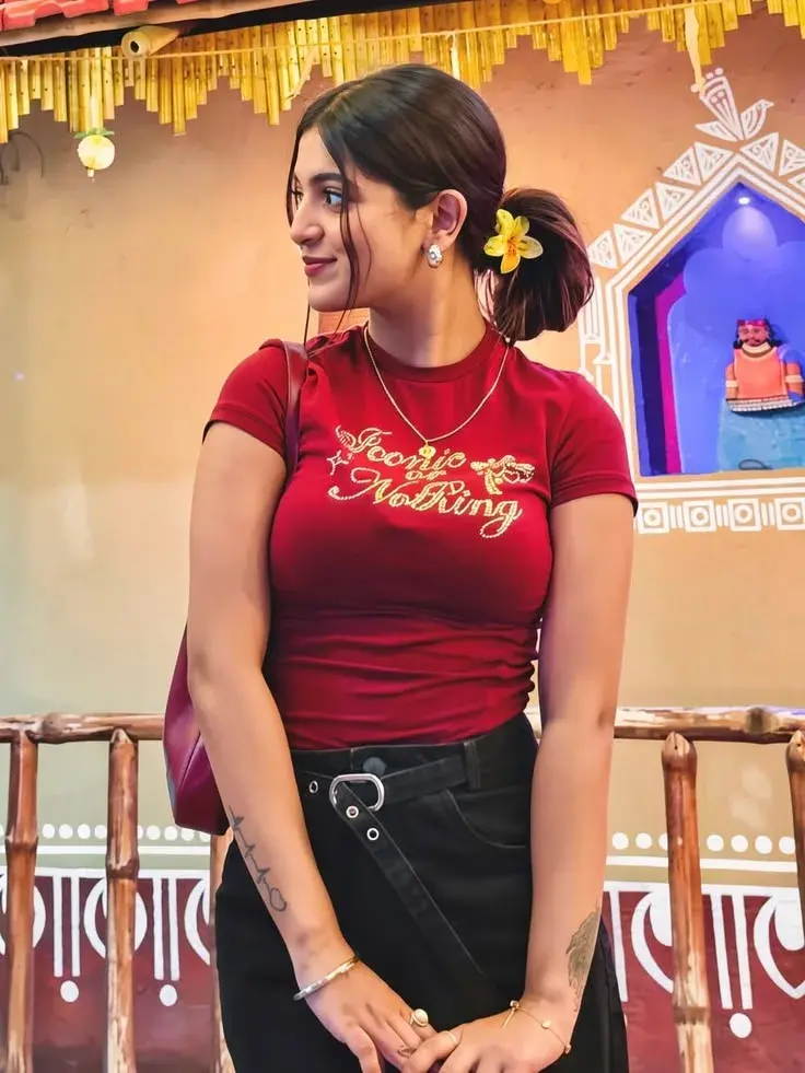Candid Heritage Village Portrait Of Beautiful Young South Asian Woman In Crimson Graphic T-Shirt With Low Bun And Flower