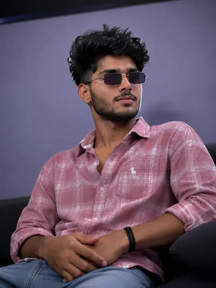 Candid Indoor Studio Portrait Of Confident Young South Asian Man In Pink Plaid Shirt And Rectangular Sunglasses