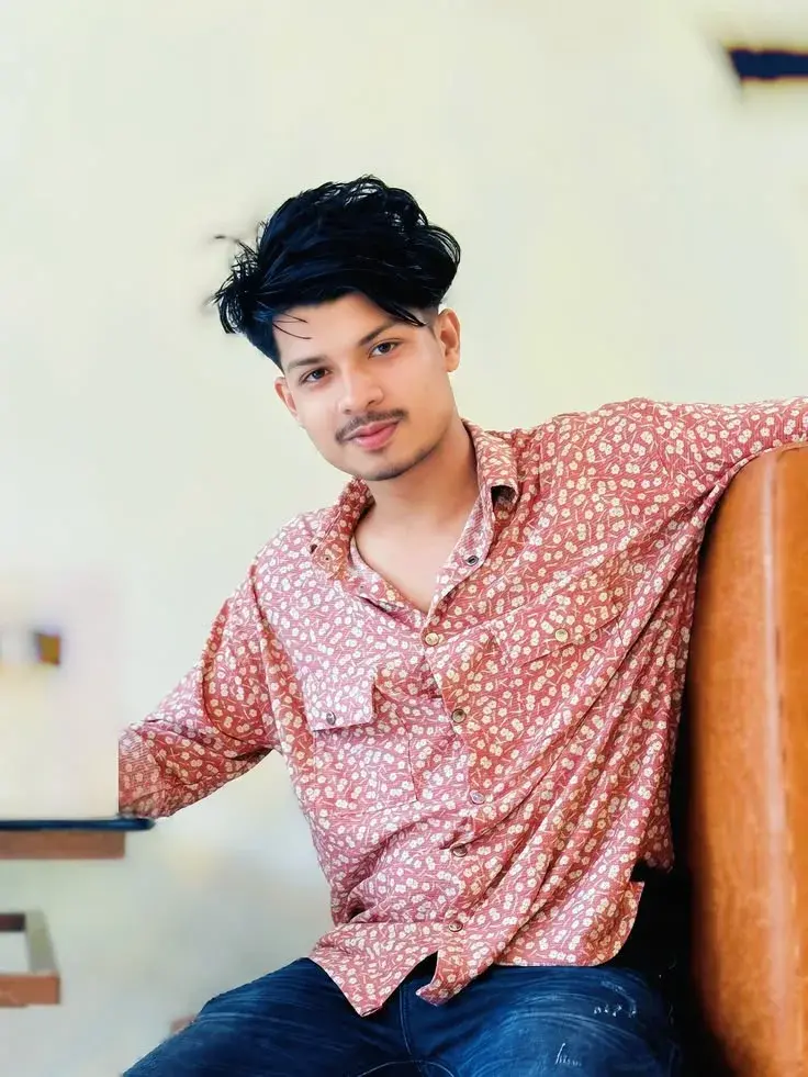 Candid Indoor Waist-Up Portrait Of Young Indian Man Seated By Cafe Booth
