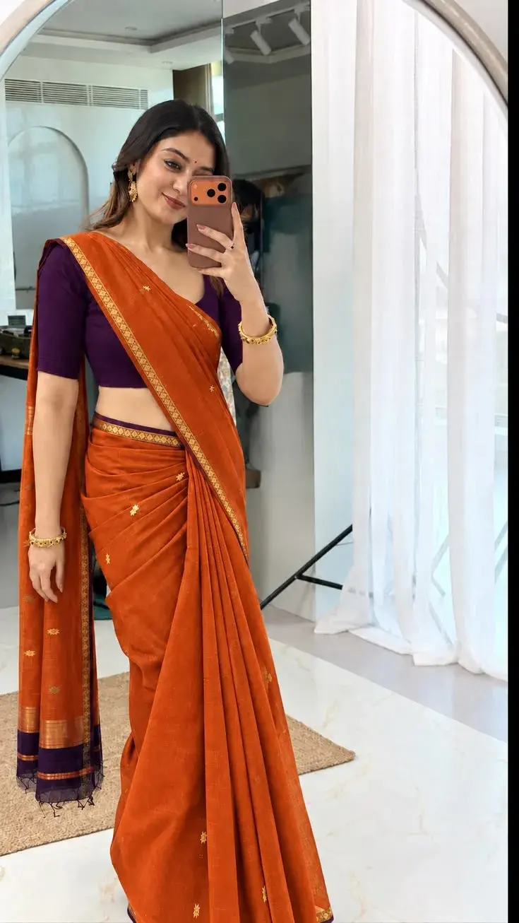 Candid Mirror Selfie Portrait Of Smiling Young South Asian Woman In Rust-Orange Linen Saree And Purple Blouse