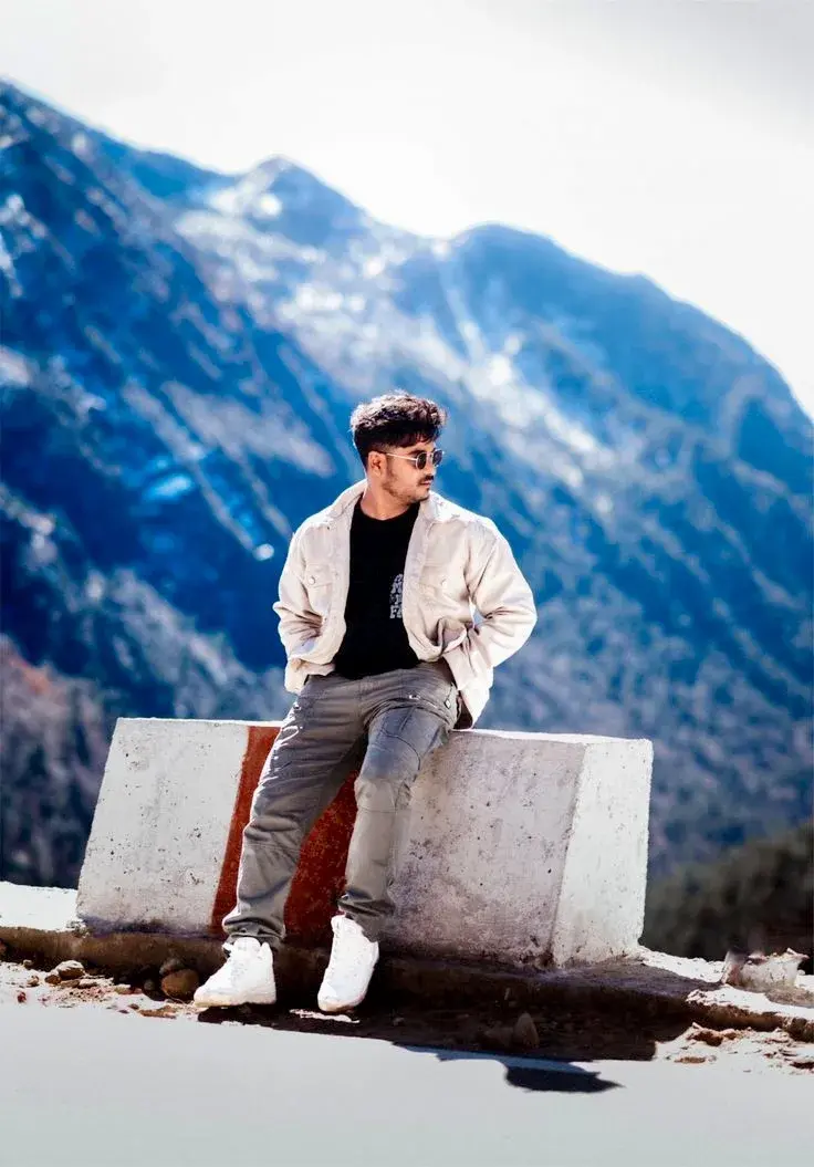 Candid Mountain Pass Portrait Of Young South Asian Man In Beige Corduroy Overshirt Leaning On Concrete Barrier