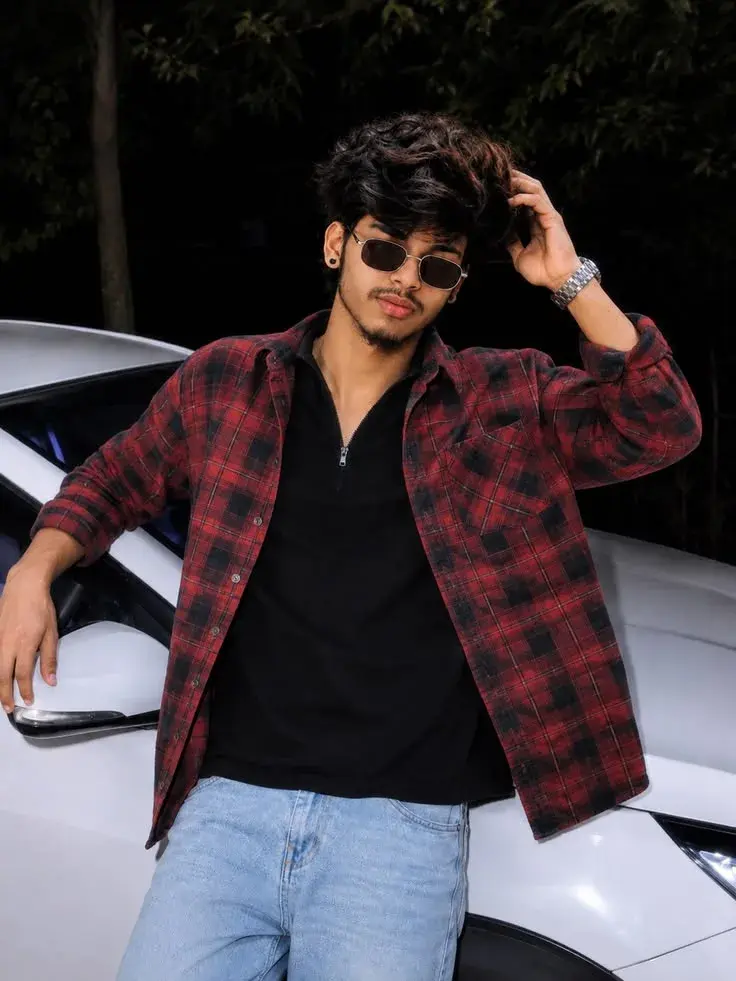 Candid Night Flash Portrait Of Stylish Young South Asian Man Leaning Against White Car In Red Plaid Flannel Shirt And Re