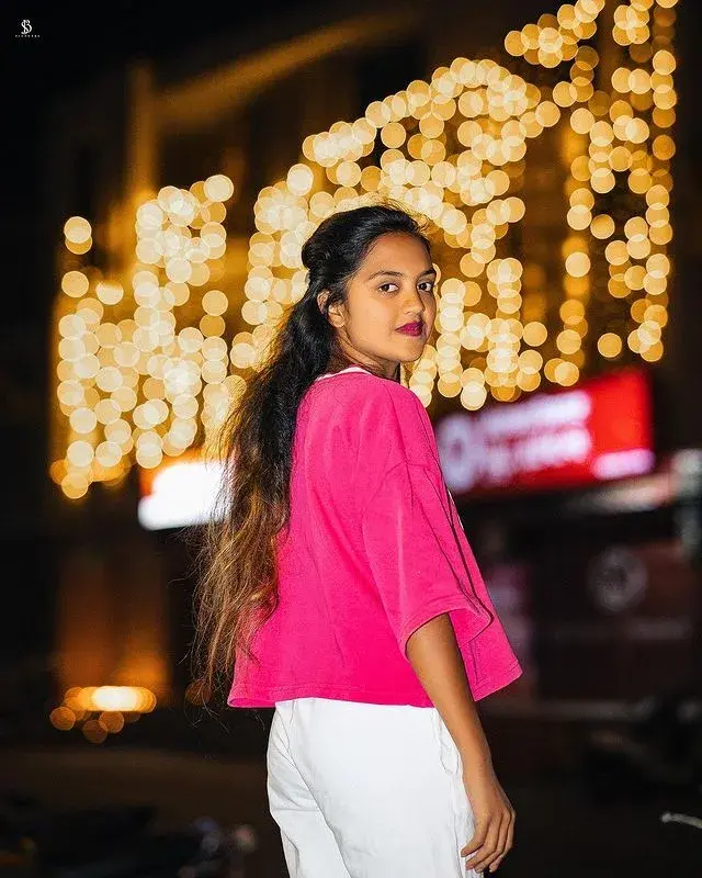 Candid Night Street Portrait Of Young South Asian Woman In Bright Pink Top With Golden Fairy Light Bokeh