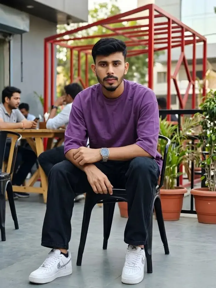 Candid Outdoor Cafe Terrace Portrait Of Young South Asian Man In Purple Oversized T-Shirt And Black Cargo Jeans