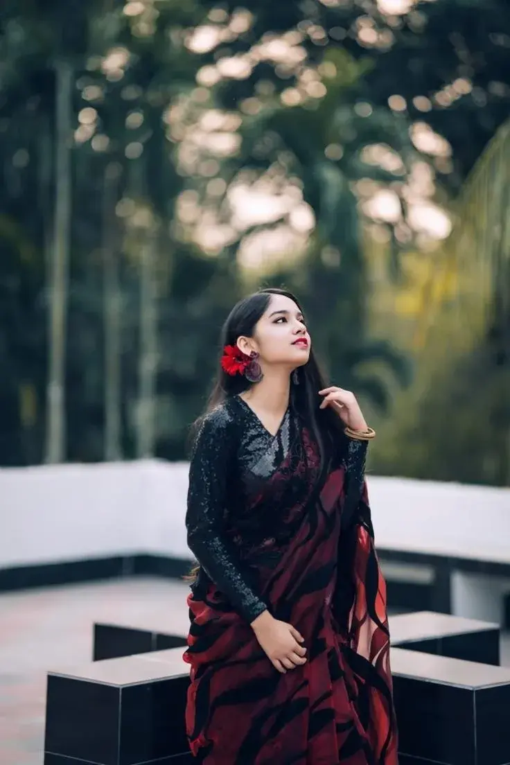 Candid Outdoor Evening Portrait Of Young Woman In Maroon And Black Sequin Saree Looking Upward