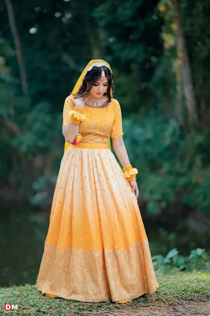 Candid Outdoor Haldi Portrait Of Young South Asian Bride In Yellow Ombre Lehenga And Floral Jewelry
