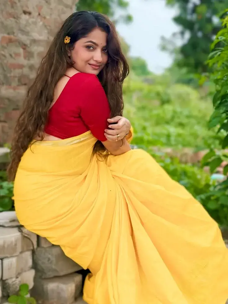 Candid Outdoor Portrait Of Indian Woman In Yellow Saree Seated On Stone Steps