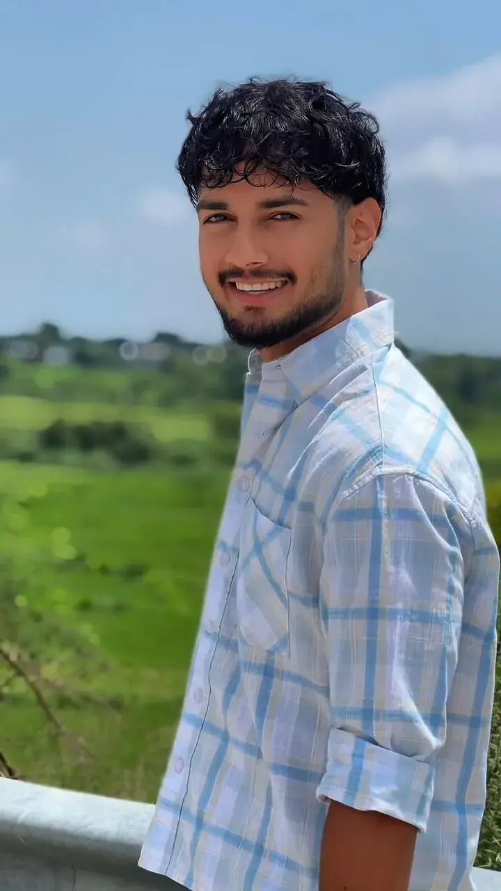 Candid Outdoor Portrait Of Smiling Young Man In Blue Checkered Plaid Shirt Leaning On Guardrail