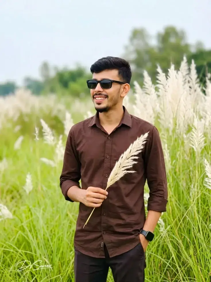 Candid Outdoor Waist-Up Portrait Of Young Indian Man Holding Kash Flower In Grassland