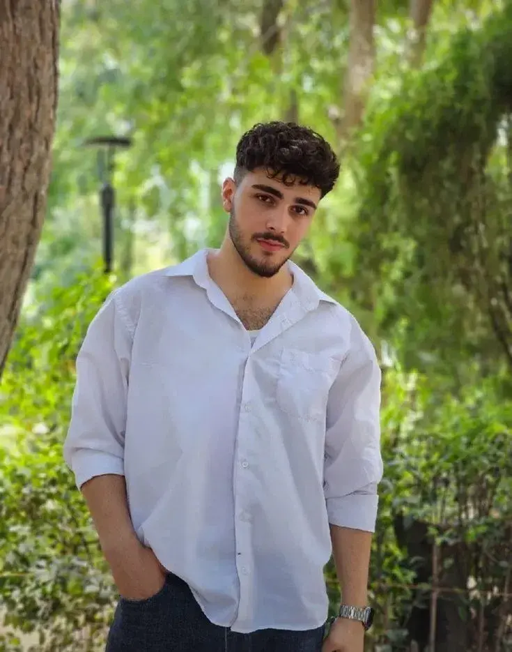 Candid Outdoor Waist-Up Portrait Of Young Man In White Shirt In Park