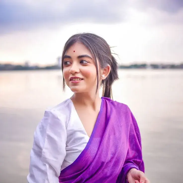 Candid Riverside Promenade Portrait Of Smiling Young South Asian Woman With Red Bindi In Purple And White Saree