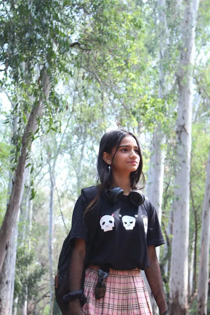 Candid Sunlit Forest Portrait Of Young South Asian Woman In E-Girl Aesthetic With Skull Graphic T-Shirt And Pink Plaid S