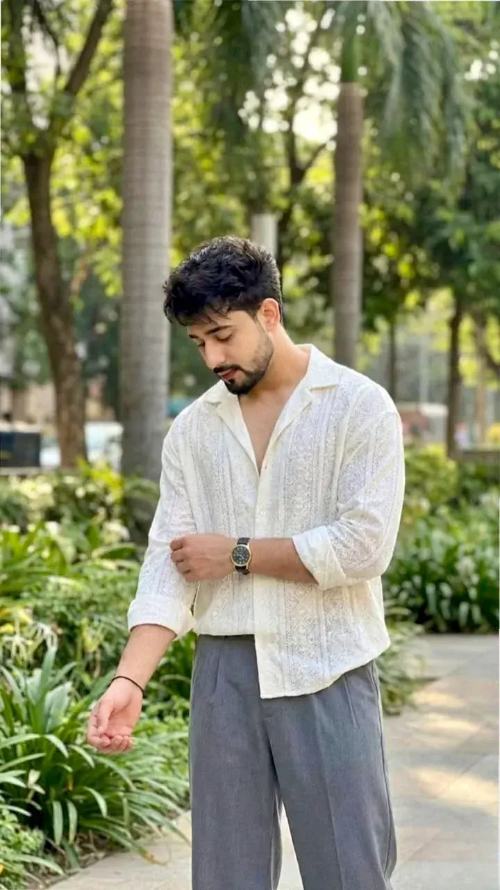 Candid Sunlit Garden Promenade Portrait Of Young South Asian Man In White Embroidered Kurta Shirt Rolling Up Sleeve
