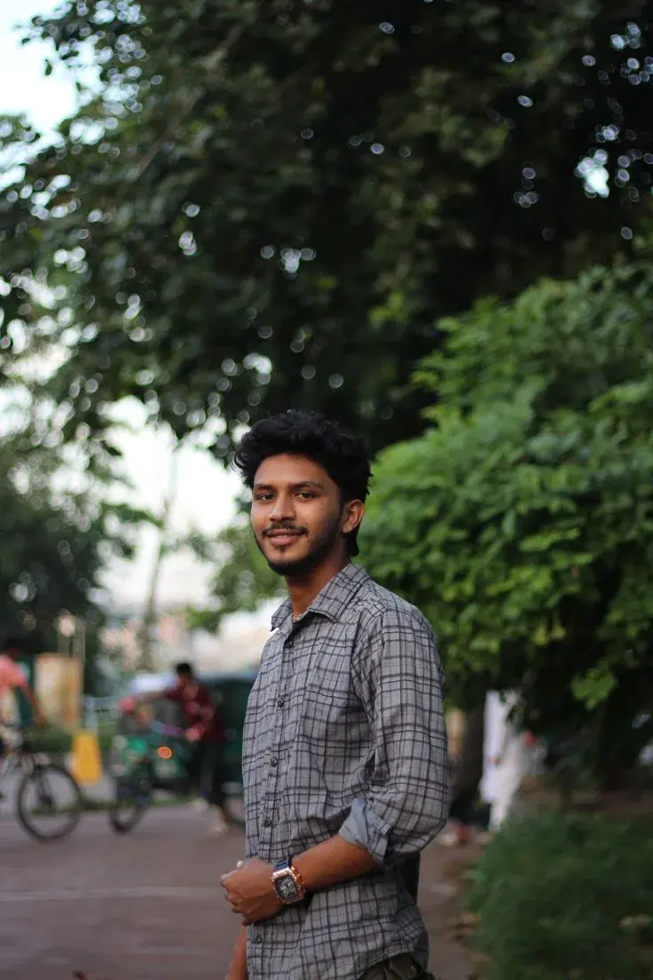 Candid Sunlit Park Promenade Portrait Of Smiling Young South Asian Man With Curly Quiff And Goatee In Grey Plaid Shirt