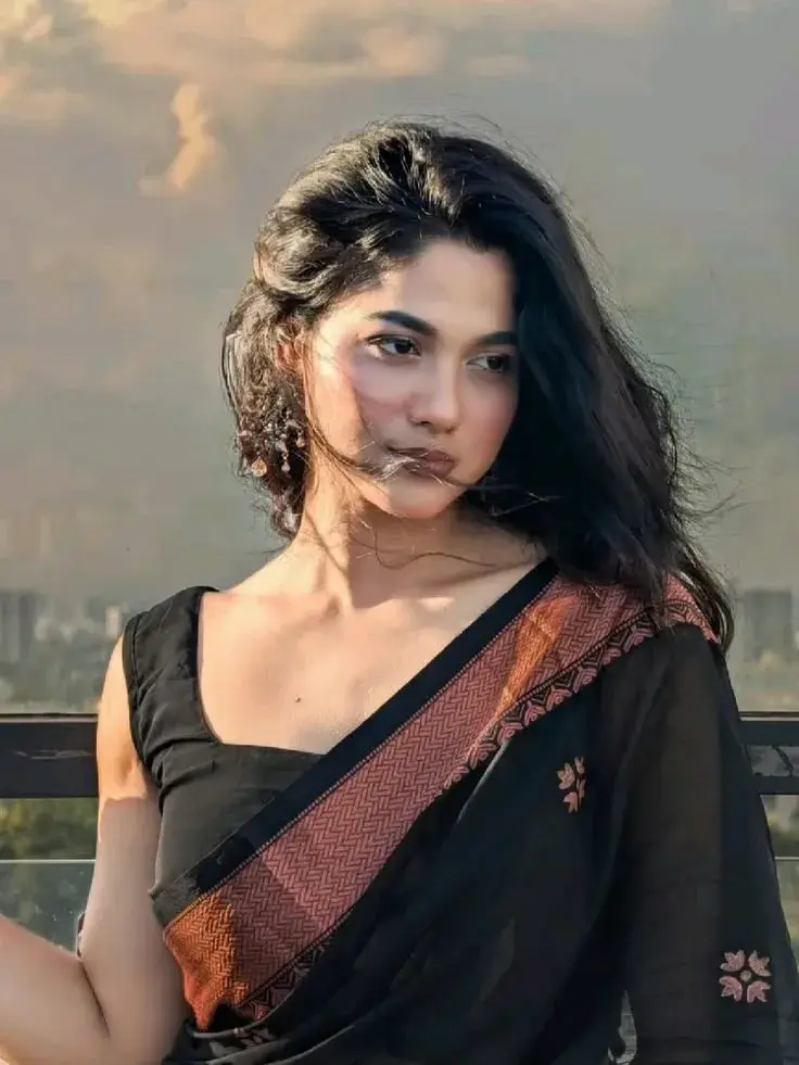 Candid Sunlit Rooftop Terrace Portrait Of Radiant Young South Asian Woman In Black Saree With Terracotta Border