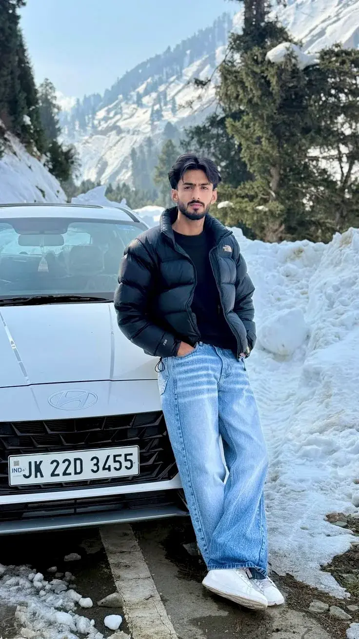 Candid Winter Portrait Of Young South Asian Man Leaning On White Car By Snowbank In Himalayan Mountains