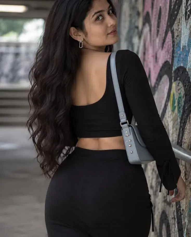 Candid Woman In Black Crop Top And Skirt Looking Over Shoulder Near Graffiti Wall