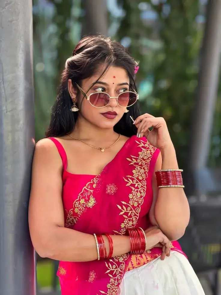 Candid Woman In Hot Pink Saree With Oval Sunglasses Leaning Against Metal Pillar