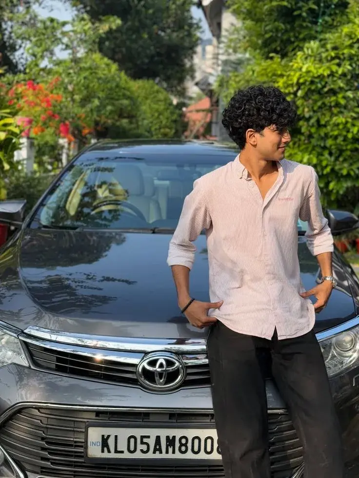 Candid Young Man In Pink Striped Shirt Leaning On Toyota Car In Driveway