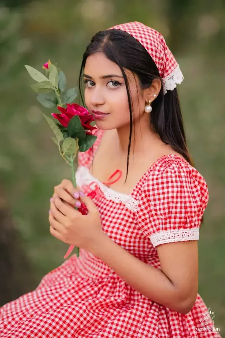Candid Young Woman In Red Gingham Dress With Bandana Holding A Red Rose