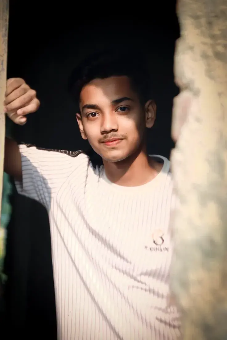Dramatic Portrait Of Young Indian Man Framed By Rustic Doorway With Natural Sunlight