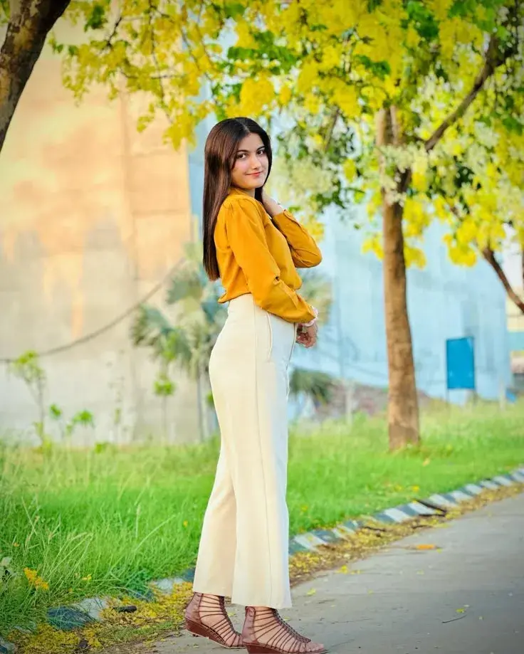 Indian Woman In Yellow Blouse And Wide-Leg Pants Under Cassia Trees