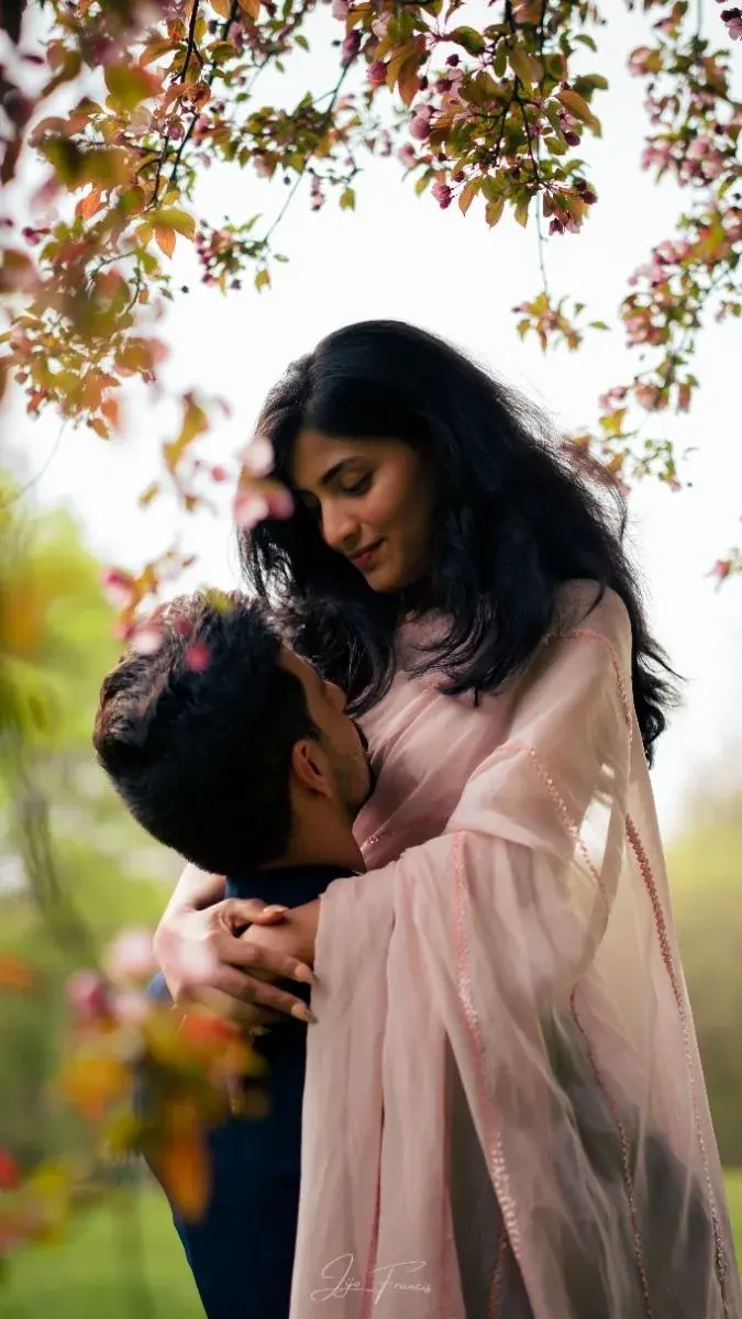 Romantic Outdoor Portrait Of Couple Embracing Beneath Blooming Spring Blossom Branches