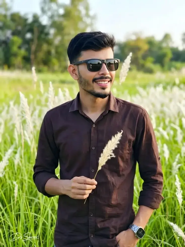 Smiling Young Man Holding Wild Grass Plume In Blooming Autumn Meadow