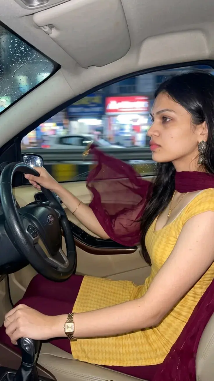 Woman Sitting In The Driver's Seat Of A Car, Dressed In Traditional Indian Attire