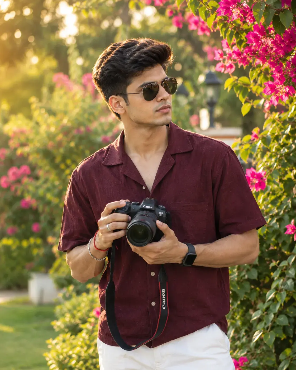 Young Man In Maroon Shirt Holding Camera In A Flowering Garden