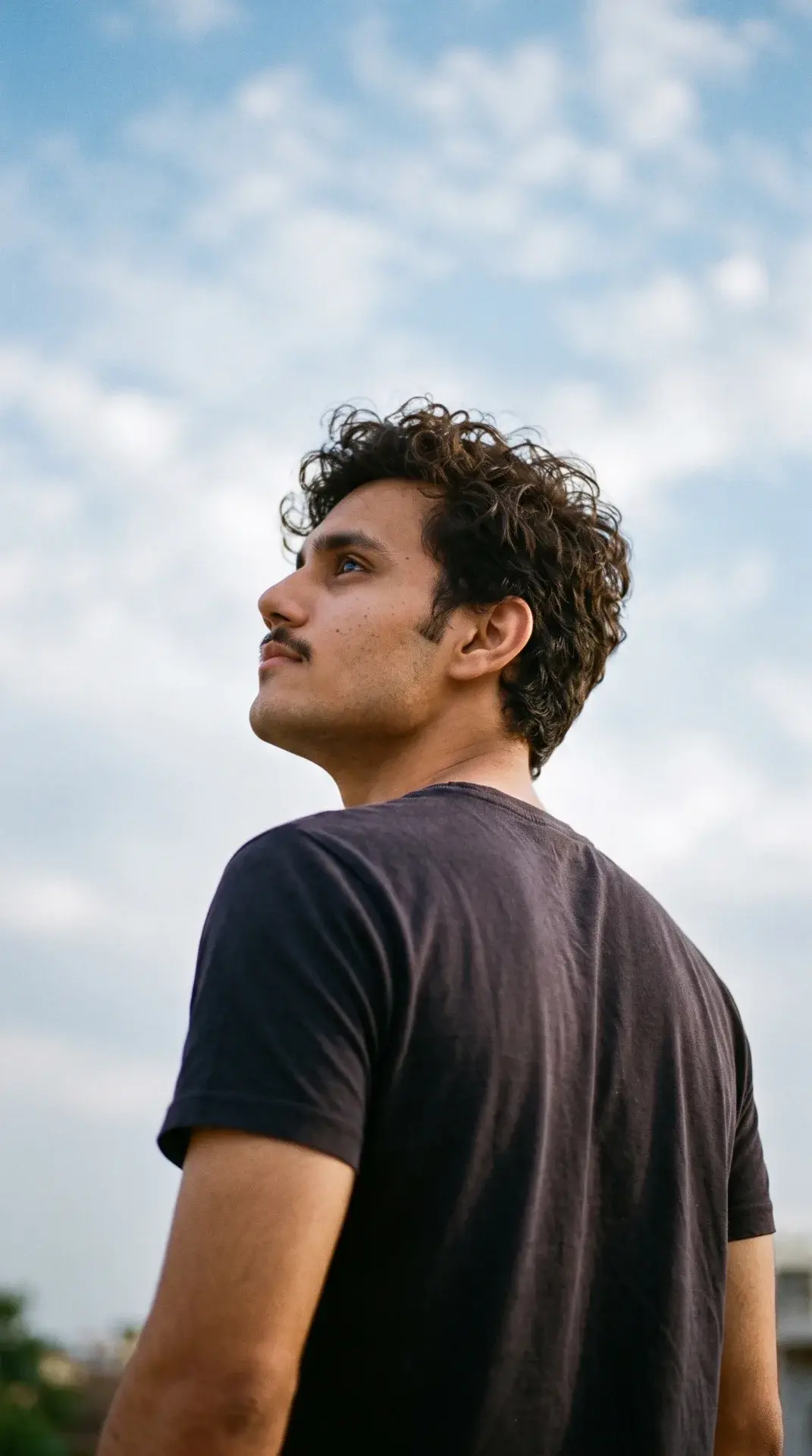 Young Man Looking Upward Against Blue Sky